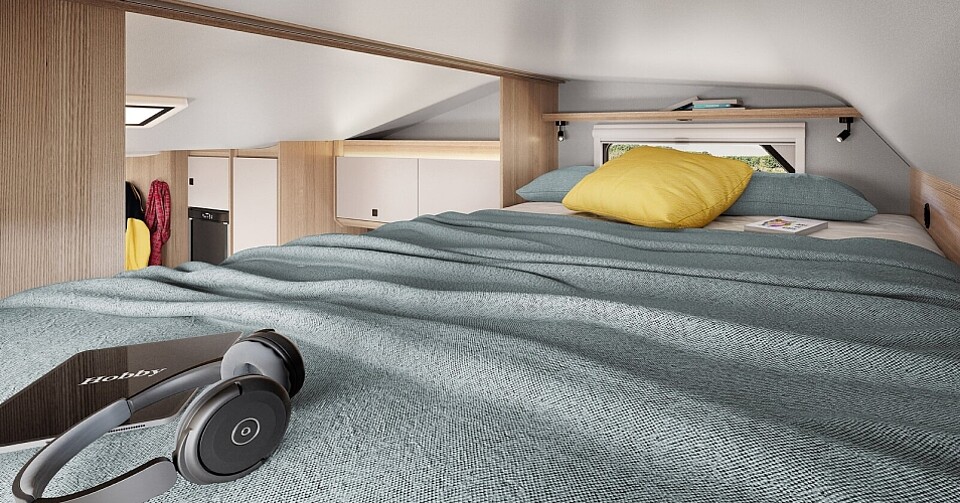 Innenaufnahme von einem gemütlichen Bett in der Alkove des Hobby Wohnmobils.